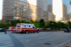 FDNY ambulance speeding down a city street with tall buildings in the background (motion blur).