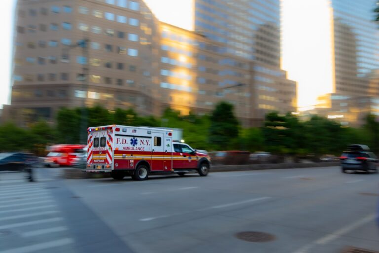 FDNY ambulance speeding down a city street with tall buildings in the background (motion blur).