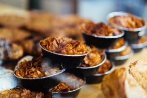 Stack of caramelized granola pastry cups in black foil cups on a bakery display table